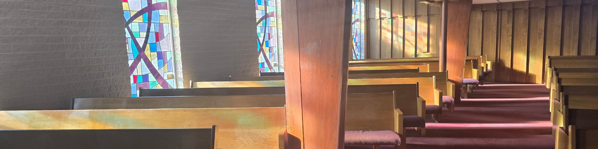 sun from stained glass shining on pews